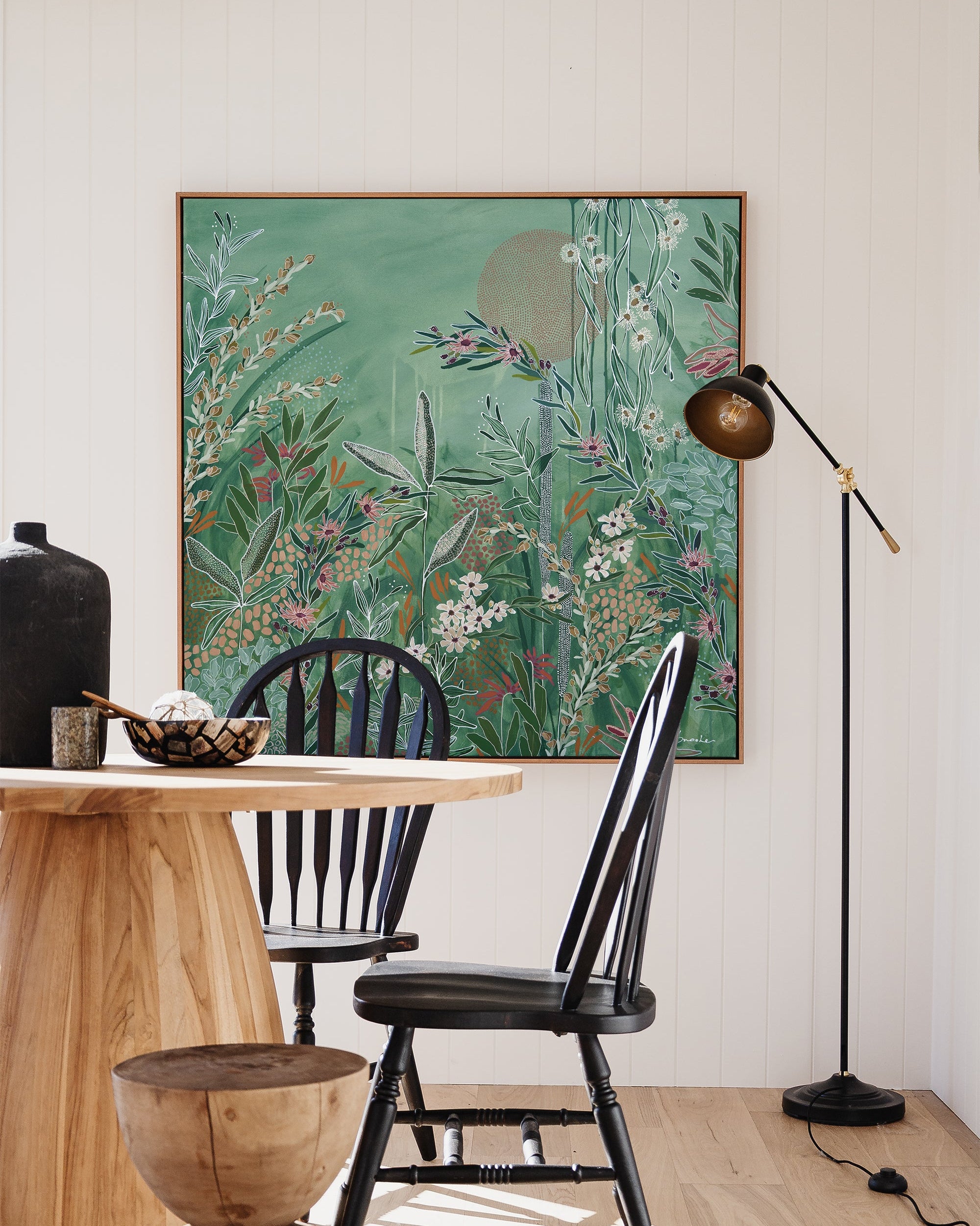 Dining room with wooden table, black chairs, and a large floral painting on the wall.