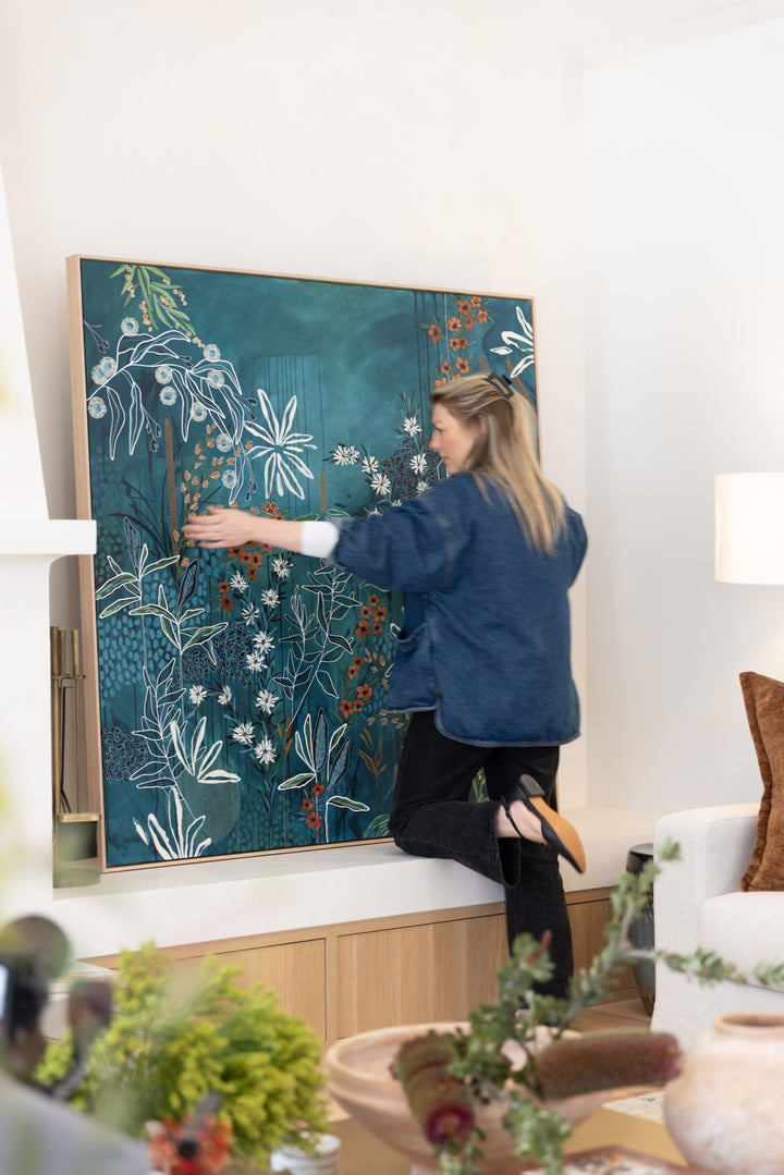 Woman interacting with a large floral painting in a modern living room.